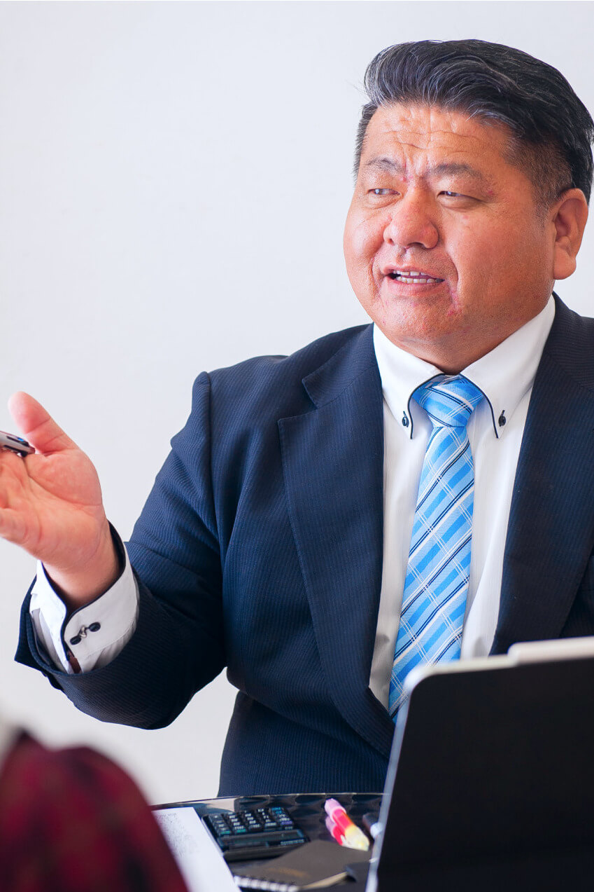 会議中の男性がペンを手にして相手に提案している場面
